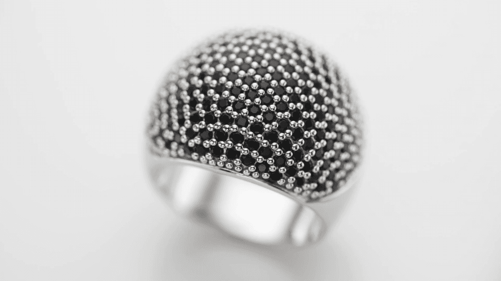 A silver pave ring photographed at macro distance with a wide aperture: only a thin band across the dome is sharp, from the Lenses chapter of the course.