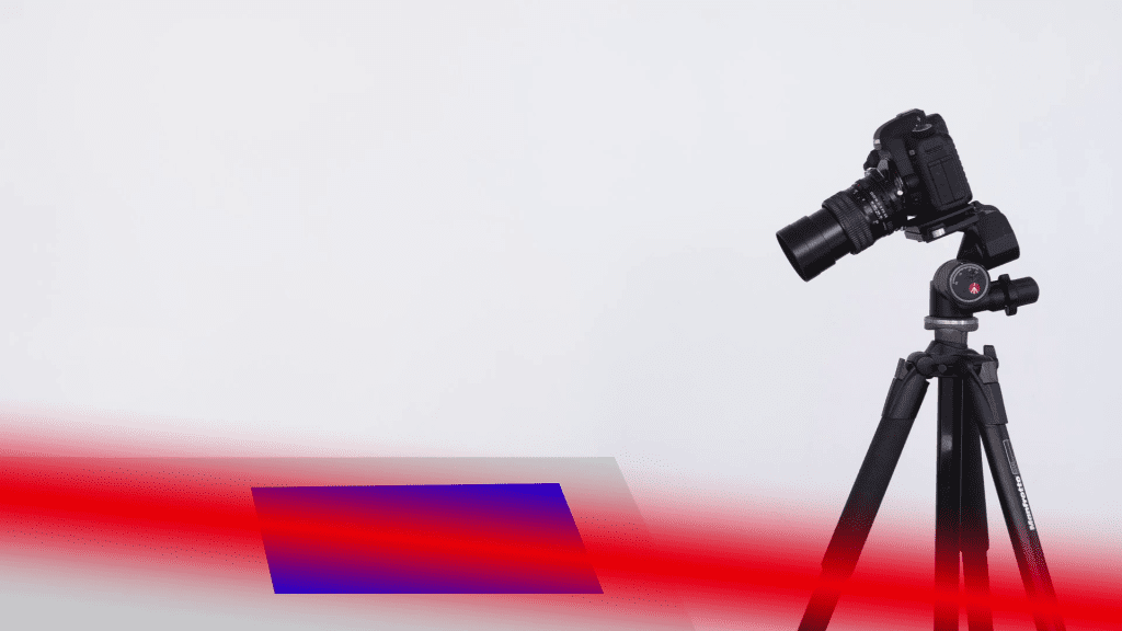 Illustration from the third Lenses lesson of the course: a camera on a tripod aimed at a small subject, with a red beam marking the optical axis and a thin blue slab marking the plane and depth of sharp focus in front of the lens.