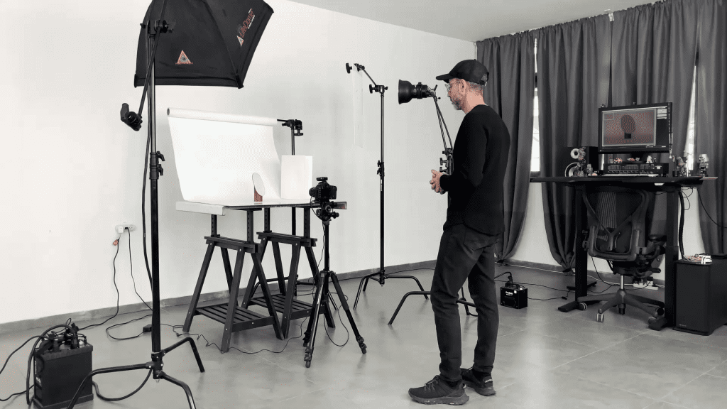 Ivan Moshe's studio during the Photographing the Mirror lesson: a table set with a mirror, a softbox over it, light stands and a tethered monitor on the desk beside the camera.
