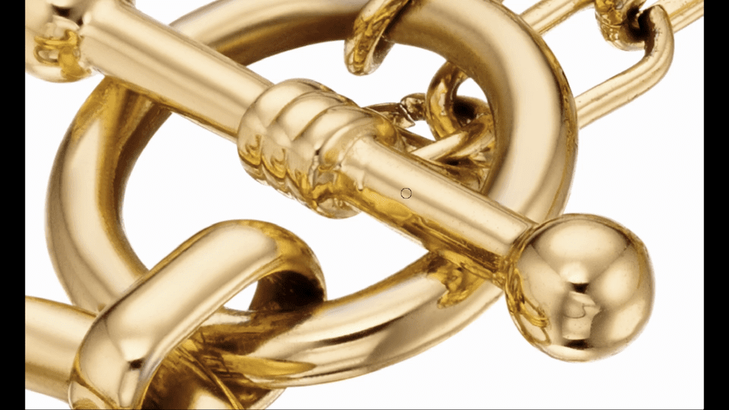 Macro view of a gold T-bar toggle clasp and chain links, photographed in the course for the Necklace Retouching lesson, filling the frame edge to edge.
