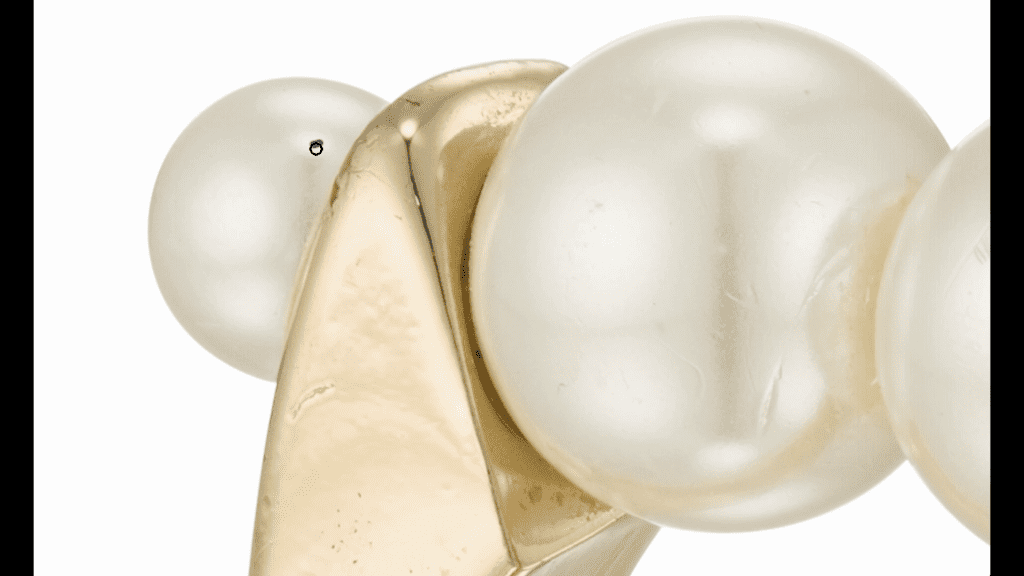 Extreme close-up of two pearls on a gold ring in Photoshop during the second Ring Retouching lesson, showing the soft highlights on the pearls and a small blemish on one surface.